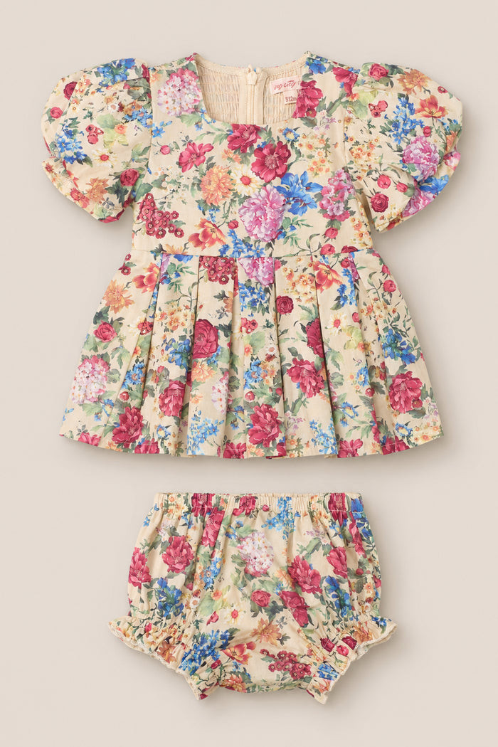 Presenting the Baby Adelpha Dress Set in Autumn Amity Floral by Ivy City Co—a delightful ensemble that includes a smocked cotton dress with short sleeves, elegantly decorated in cream, pink, red, blue, and green floral hues. The set comes with matching bloomers and is showcased laid flat against a neutral background.