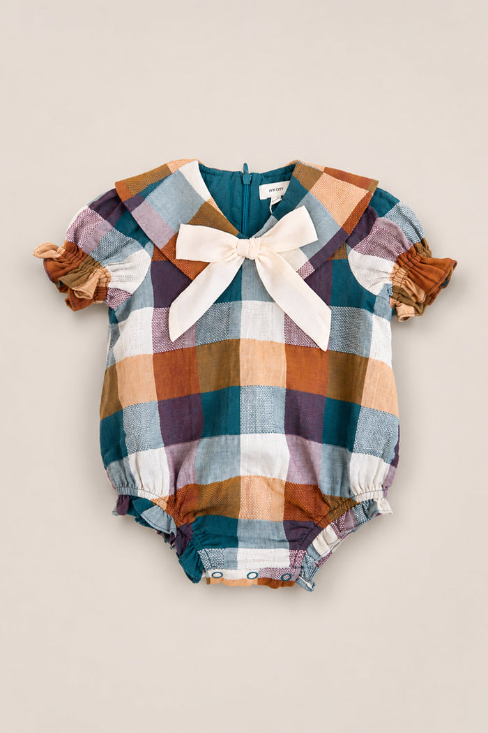 The Baby Alice Romper in Maize Gingham by Ivy City Co showcases a delightful yellow gingham pattern, short puff sleeves, a statement cream bow at the collar, and easy bottom snaps. Made from a comfortable cotton-blend fabric, this romper is perfect for playful occasions while keeping your little one stylish and cozy.