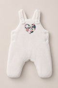 The Baby Siena Onesie in Ivory & Midnight Garden by Ivy City Co is a white fleece baby romper with shoulder straps and side buttons, adorned with a heart-shaped floral patch on the chest—an irresistibly cozy sleeveless piece that will keep your little one warm and stylish.