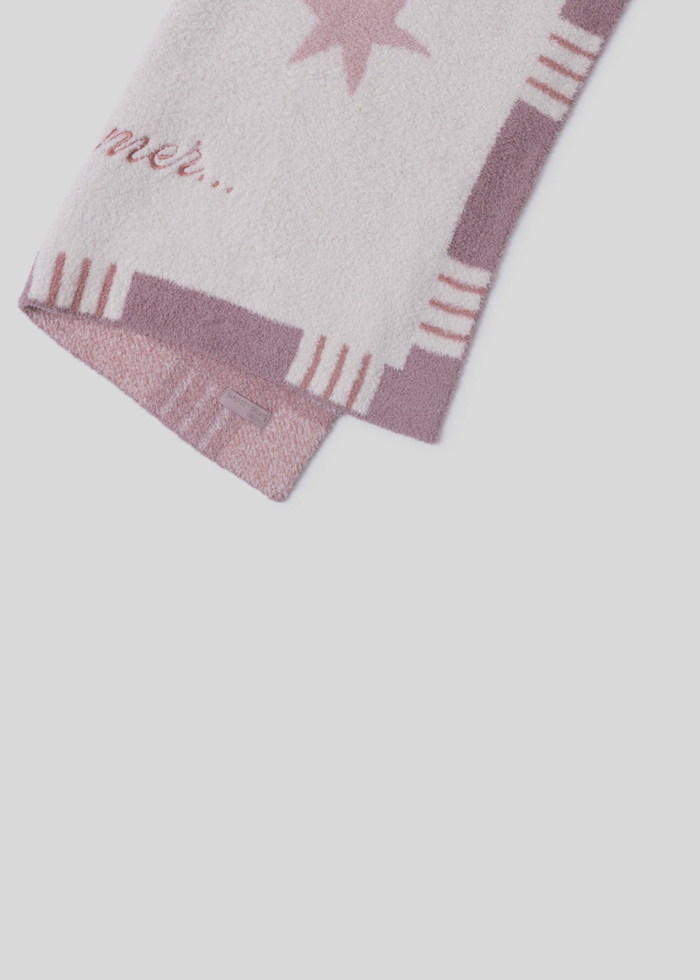 Pink blanket with stars and a striped border and "daydreamer..." pink embroidery folded in half