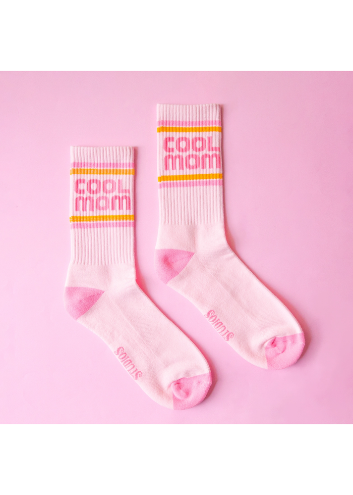 Light pink crew socks with a "Cool Mom" graphic and stripes against a pink background