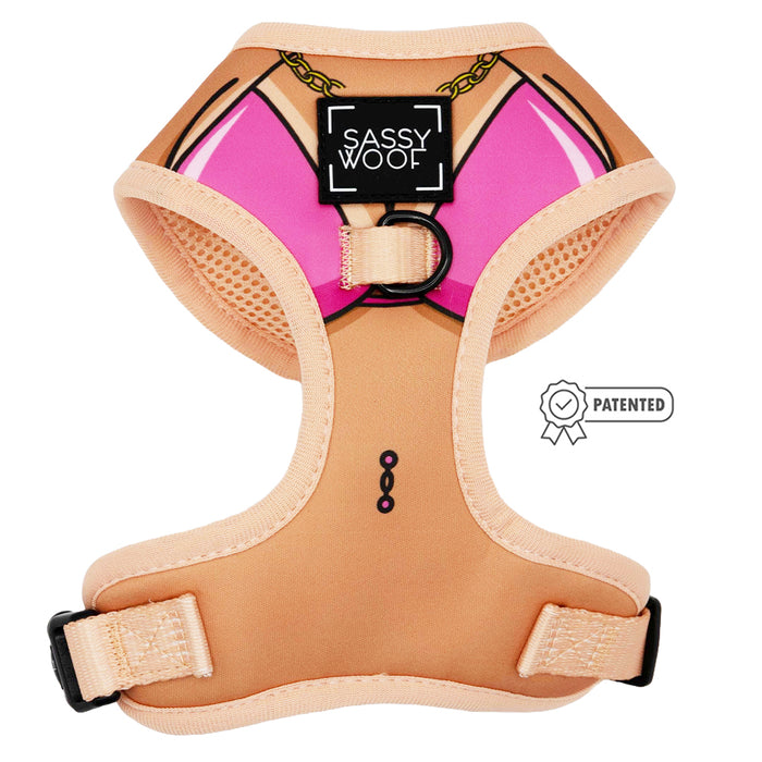 The Sassy Woof Dog Adjustable Harness in Bikini Bod features a beige base with pink print, black buckles, and a patented badge icon next to the front “Sassy Woof” label.