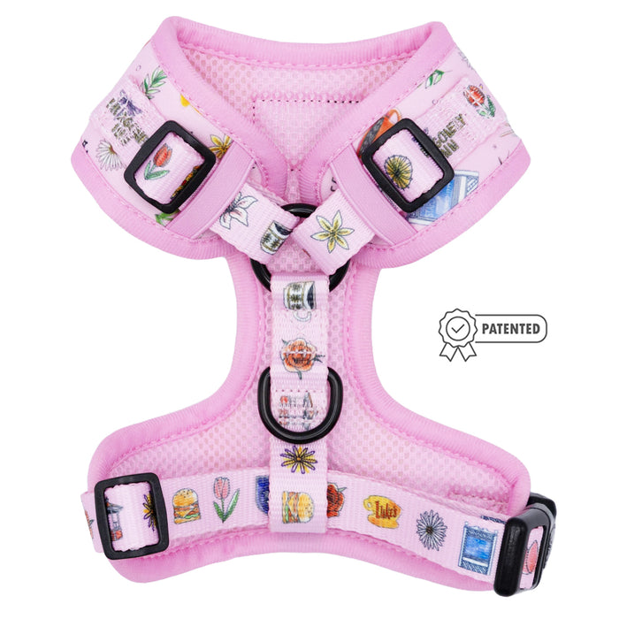 The Dog Adjustable Harness - Gilmore Girls™ by Sassy Woof features a pink design with mesh lining, playful prints of flowers, food, and objects, plus a patented badge on the right—ideal for any Stars Hollow pup.