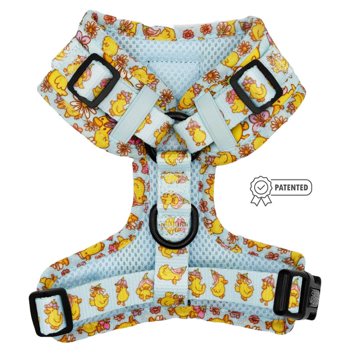 The Sassy Woof "Dog Adjustable Harness - Good Duck, Babe!" is a light blue mesh harness with floral print and a yellow cartoon duck. It features adjustable straps, black plastic buckles, and a patented badge—perfect for your puppy’s growth.