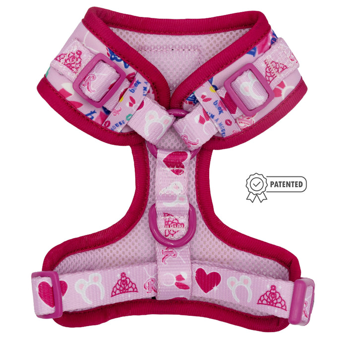The Sassy Woof Dog Adjustable Harness - Mean Girls™ is a pink and purple harness with heart, crown, and paw print designs, adjustable straps, plastic buckles, and a PATENTED ribbon icon displayed on the right side.