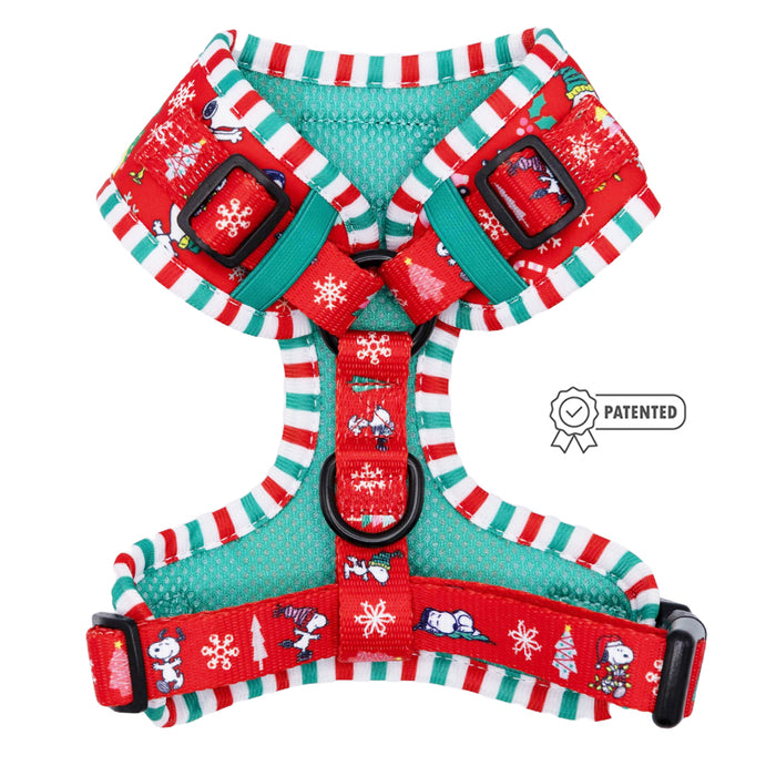The Sassy Woof Dog Adjustable Harness - Peanuts™ Beagle Bells features red and green festive holiday patterns with snowflakes, Christmas trees, and cartoon Snoopy dogs. A patented badge icon appears next to the harness.