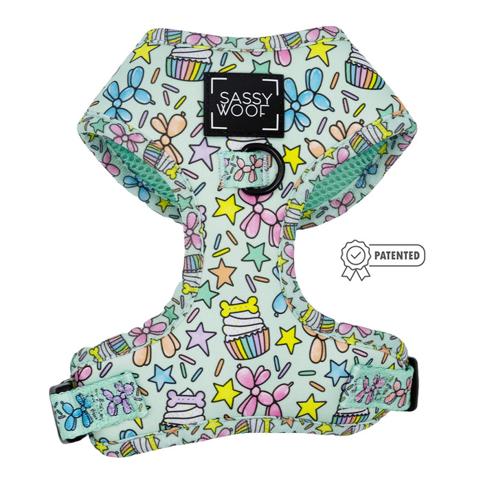 The Sassy Woof Dog Adjustable Harness - Pup Pup Hooray features a pastel cupcake, star, and bow pattern on light blue, adjustable straps for growing pups, a Sassy Woof label, and a small patented icon.