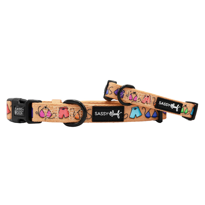 Two tan Sassy Woof Beach Bod adjustable dog collars with black buckles, featuring colorful beach accessories. Made of comfy neoprene and finished with a Sassy Woof logo tag—ideal for your puppy’s growth!.