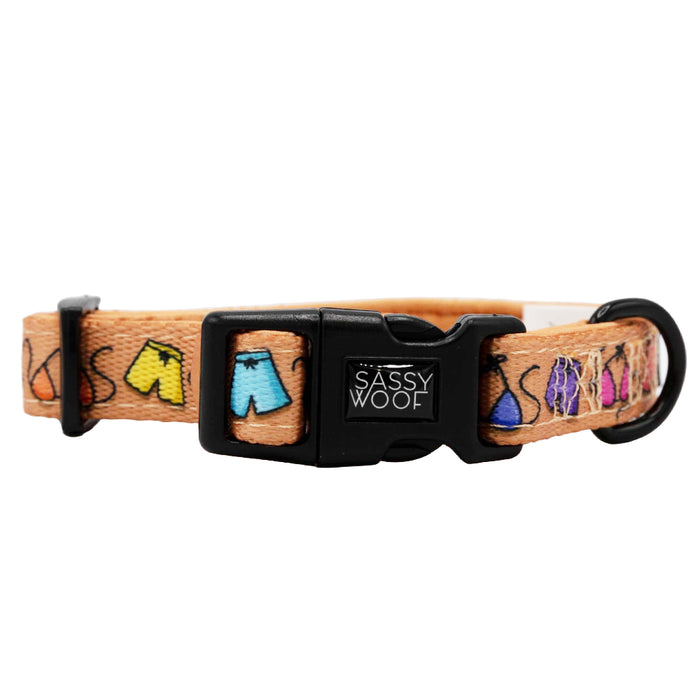 The Sassy Woof Dog Collar - Beach Bod is a tan adjustable collar with a black plastic buckle, featuring colorful shorts prints in yellow, blue, purple, and pink—ideal for your growing puppy.