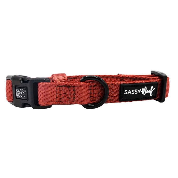 The Sassy Woof Dog Collar - Burgundy features a woven adjustable design, black plastic buckle, sturdy metal D-ring, and a branded Sassy Woof logo patch on the side.