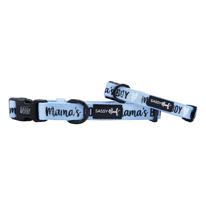 The Sassy Woof Dog Collar - Mama's Boy is a light blue neoprene collar with black hardware, an adjustable fit, white heart accents, and “Mama’s Boy” in black text along the length.