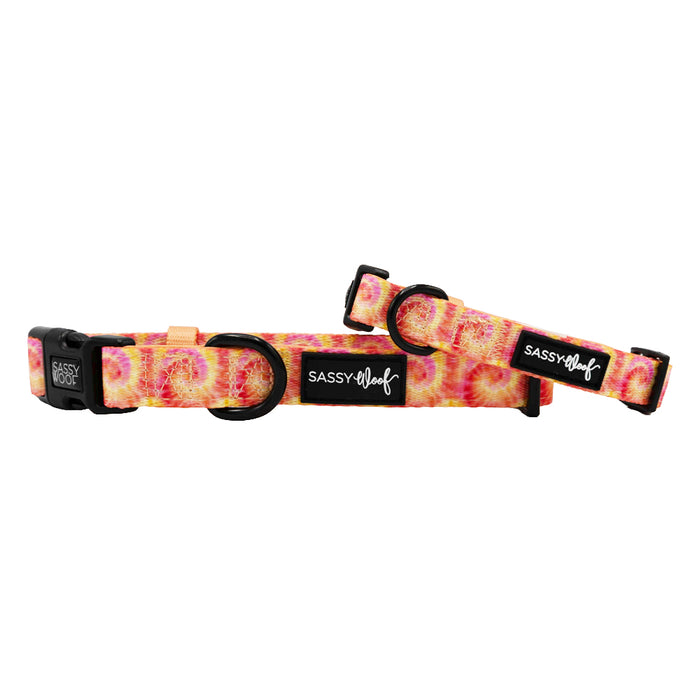 Two "Sassy Woof" Dog Collar - Summer Sorbet adjustable neoprene collars with plastic buckles, featuring a vibrant pink, yellow, and orange tie-dye pattern. Both are shown on a white background.