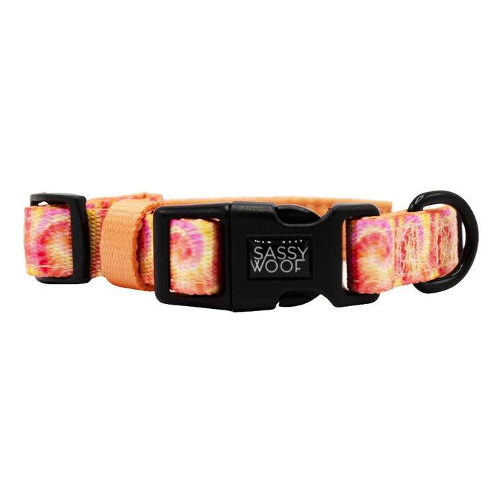 The Sassy Woof Dog Collar - Summer Sorbet features a pink, orange, and yellow tie-dye design, adjustable fit for growing puppies, a black plastic Sassy Woof buckle, and a metal D-ring for leash attachment.