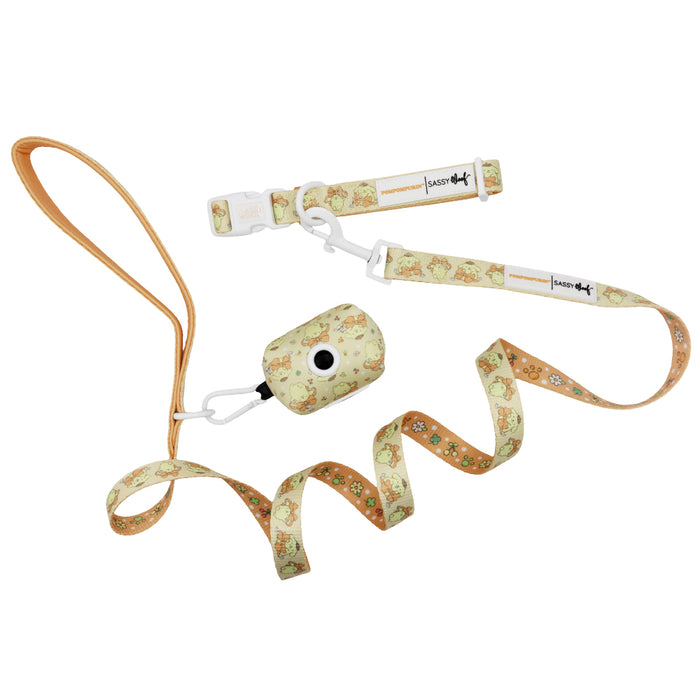 Introducing the Dog Collar Three Piece Bundle - Pompompurin™ from Sassy Woof: This adorable set features a dog leash with a tan handle, a matching collar, and a waste bag holder that conveniently clips on. Each piece is adorned with playful cartoon dog illustrations and white flowers on a pale yellow background, offering charming Sanrio-inspired style for your pup.