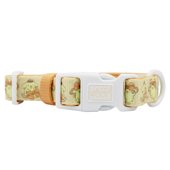 The Sassy Woof Dog Collar Three Piece Bundle - Pompompurin™ is a beige and tan collar with a white plastic buckle, featuring a subtle dog print pattern inspired by popular Sanrio dog accessories and a metal ring for attaching a leash.