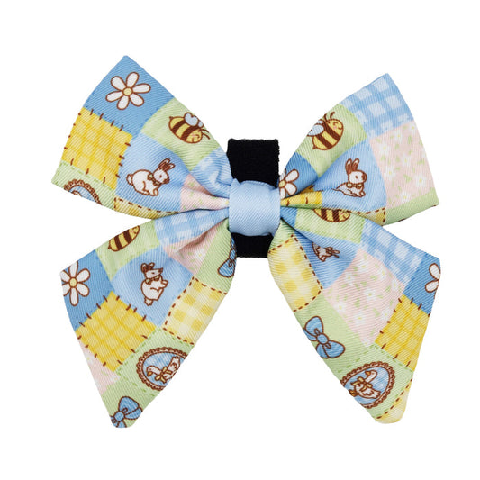 The Sassy Woof Dog Sailor Bow - Patch Perfect features a pastel picnic pattern with blue, yellow, and green squares, bunnies, flowers, butterflies, polka dots, and quilted designs.