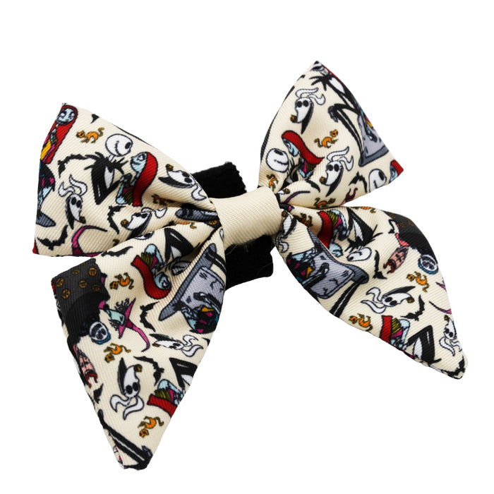 The Sassy Woof Dog Sailor Bow - The Nightmare Before Christmas™ (Beige) features a cream base with colorful cartoon skeletons, jack-o’-lanterns, and bats, and easily attaches to any dog collar with its black band.