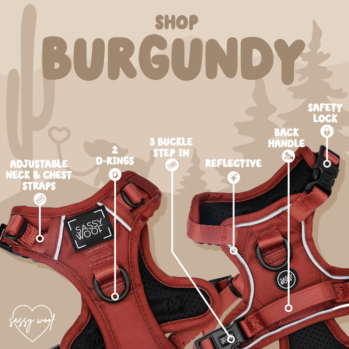 The Sassy Woof Dog Step-in Harness in Burgundy features adjustable neck and chest straps, dual D-rings, three buckles, reflective safety material, a back handle, and a safety lock. Displayed on a tan background with trees and cactus illustrations.
