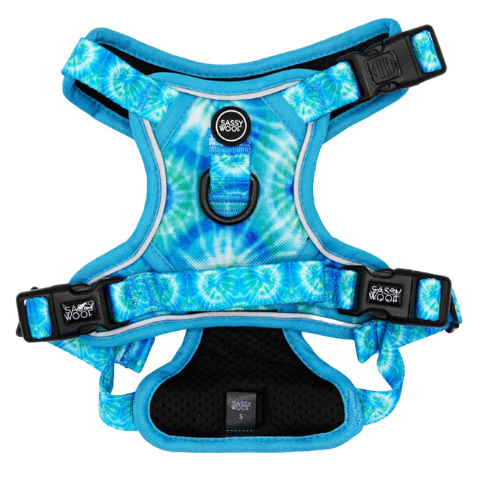 The Sassy Woof Dog Step-in Harness - Tropical Tides features a blue and white tie dye design, black buckles, front D-ring, padded chest panel, and a logo patch for style and convenience.