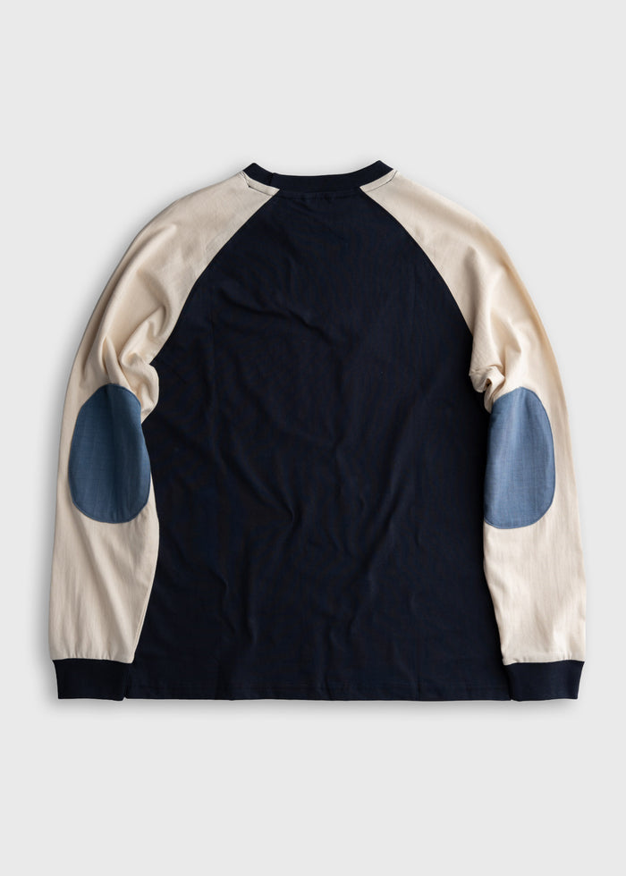Long-sleeve shirt with navy body, cream sleeves, and blue elbow patches, laid flat on a light background.
