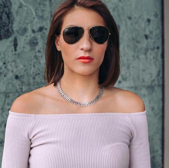 Silver statement necklace, textured design, worn with off-the-shoulder top.