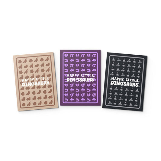 Three notebooks with "Happy Little Dinosaurs: Hazards Ahead Card Sleeves" text, in beige, purple, and black, each featuring outlines of cartoon dinosaurs.
