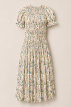 The Jennifer Dress in Autumn Bouquet by Ivy City Co is a light cream dress adorned with a floral print, featuring short puff sleeves, a smocked bodice for comfort, and a gathered midi-length skirt. Maternity friendly and effortlessly elegant, it’s showcased against a plain background.