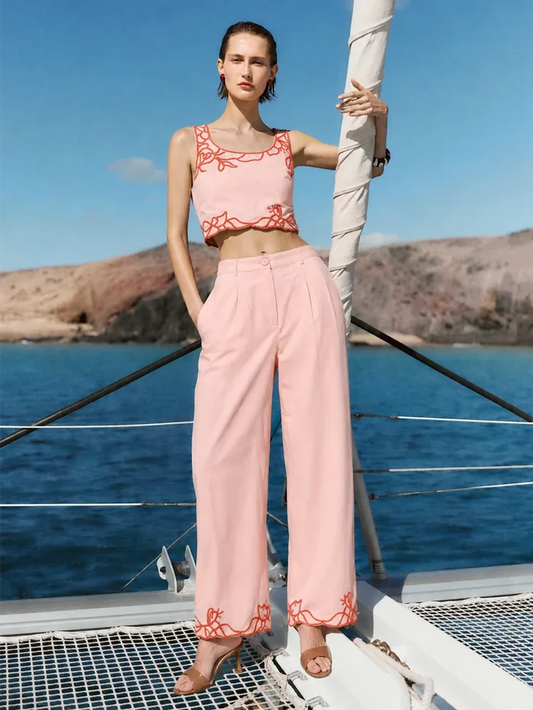 Woman in a pink outfit standing on a boat with a scenic background