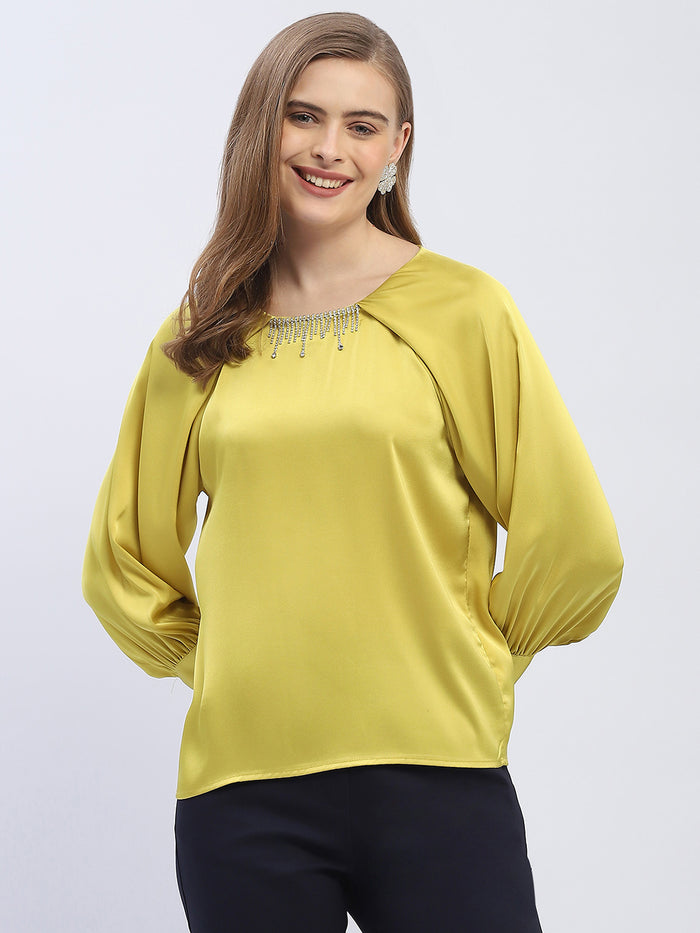 Woman wearing a yellow blouse with long sleeves on a light gray background
