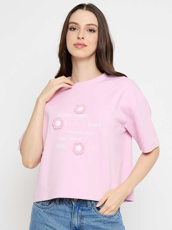 Woman wearing a pink t-shirt with floral designs on a white background