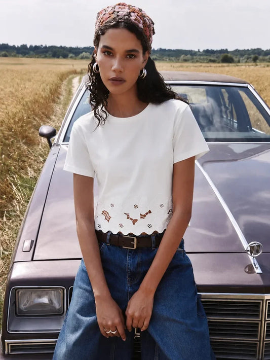 Woman sitting on a vintage car in a field