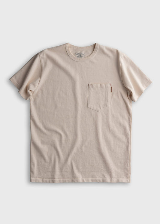 Beige crewneck T-shirt with a chest pocket, displayed on a plain background. Simple, casual design with soft fabric texture.