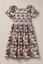 Introducing the Mini Sunday Best Dress in Midnight Garden by Ivy City Co—a charming mini dress showcasing a colorful floral pattern on a light background. Designed with short puff sleeves, a smocked bodice, and a square neckline, it features a gathered skirt for an effortlessly sweet look.
