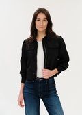 Woman with dark hair posing in black jacket with hand on the zipper.