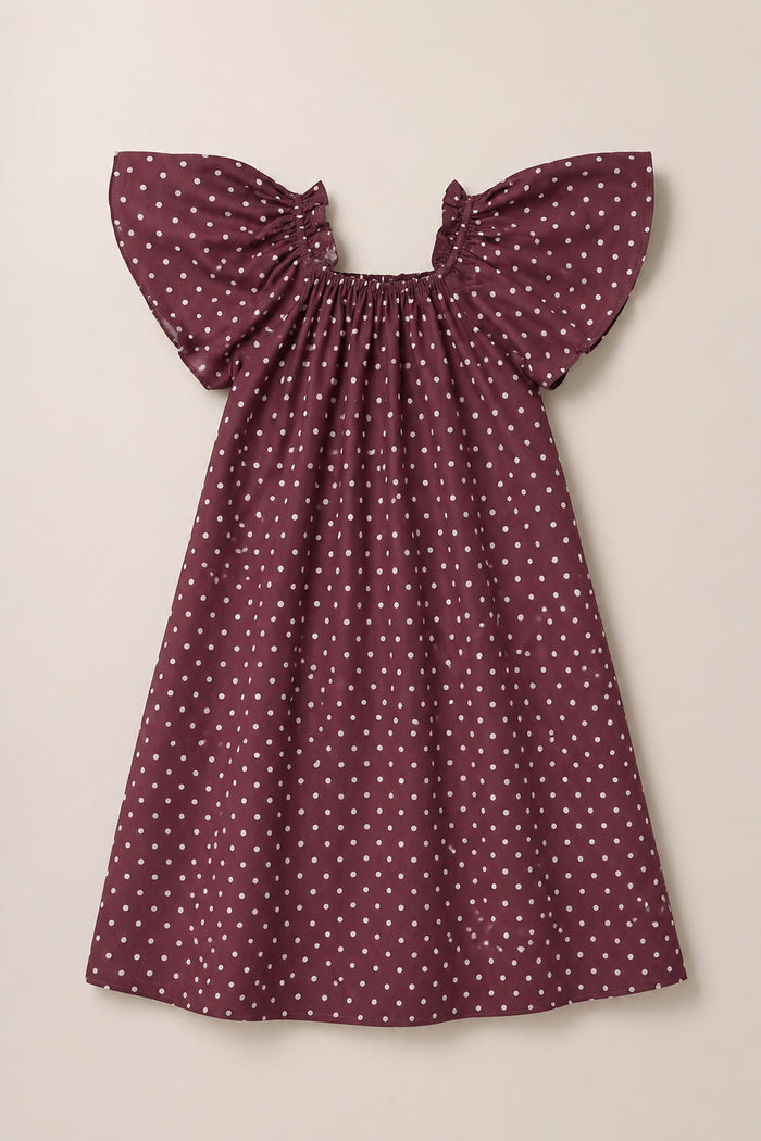The Ivy City Co Teen Blakely Dress in Aubergine Ditsy Dot features short, flutter sleeves and a gathered neckline with a smocked bodice, adorned with white polka dots and displayed on a neutral background.
