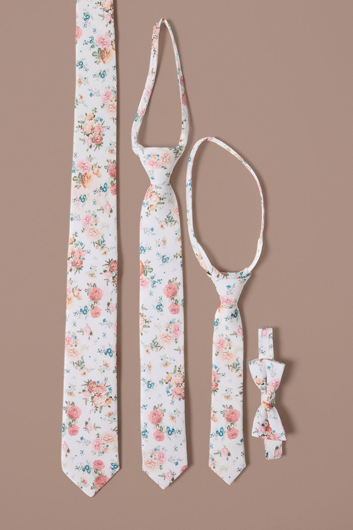 The Ivy City Co Ties in Countryside Peony Blossom set includes two neckties, one child-sized necktie, and one bow tie—all with a floral print—perfect for family coordination and displayed on a light brown background.