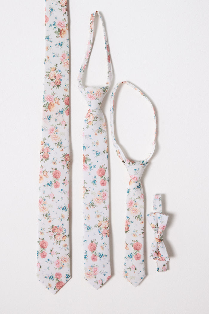 The Ties in Countryside Peony Blossom set by Ivy City Co features four matching accessories—adult, child, and baby neckties plus a family bow tie—in a pink, blue, and green floral pattern on white. All are displayed on a white background.