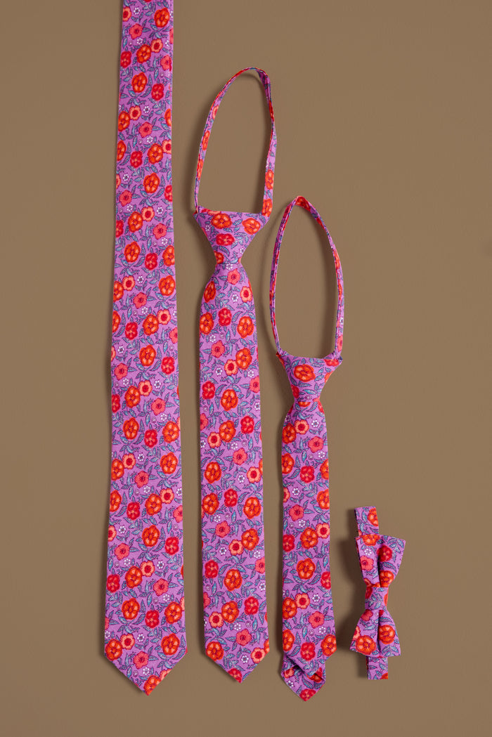 Three Ties in Thistle Flower Poppy Woodblock by Ivy City Co and one matching bow tie, all with a vibrant red and purple floral pattern, are arranged vertically on a brown background—perfect for family or mom and me sets.