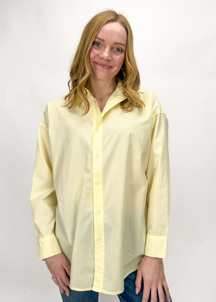 Woman wearing a light yellow button-up shirt against a white background